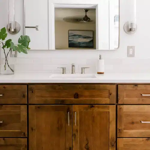 Wood vanity with white countertop mirror and sconce lights