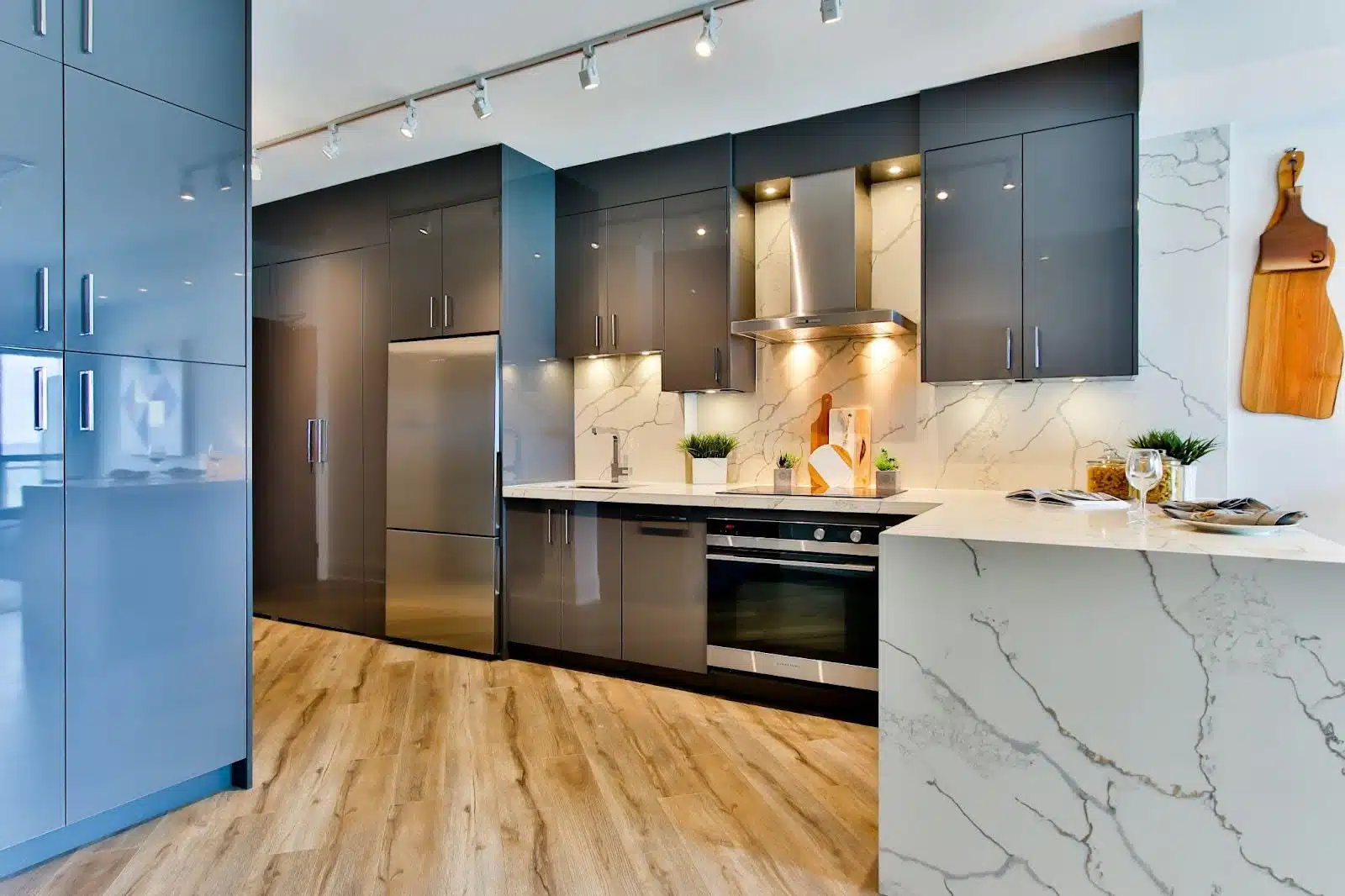 A contemporary kitchen featuring sleek marble countertops and backsplash, complemented by stylish slate gray and azure cabinets.