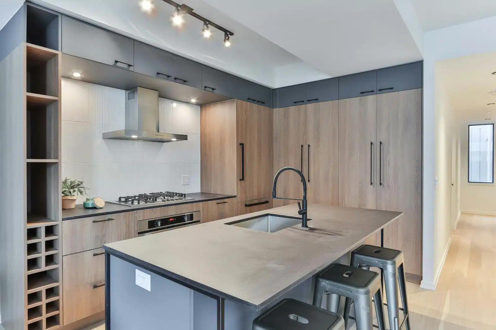 A sleek, modern kitchen with wood cabinets, an island with a built-in sink, gas stovetop, and under-cabinet lights.