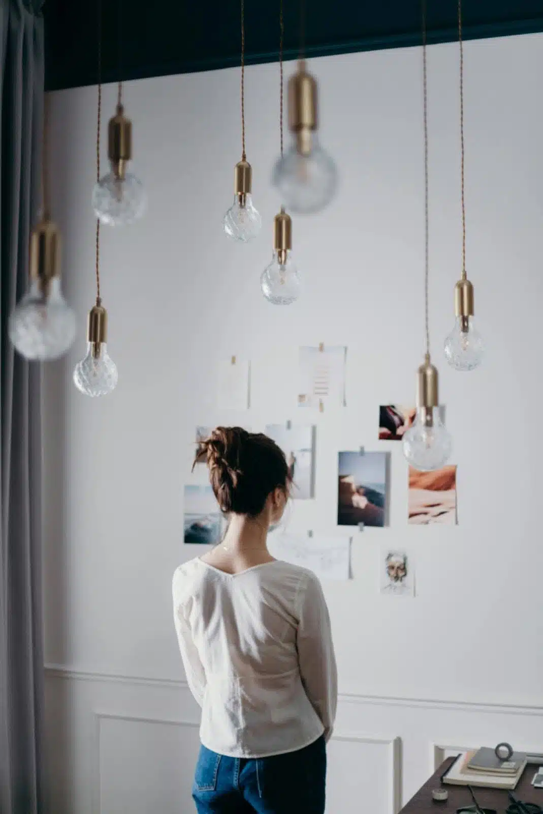 Woman Under Pendant Lights Looking at the Photo on the Wall<br />
