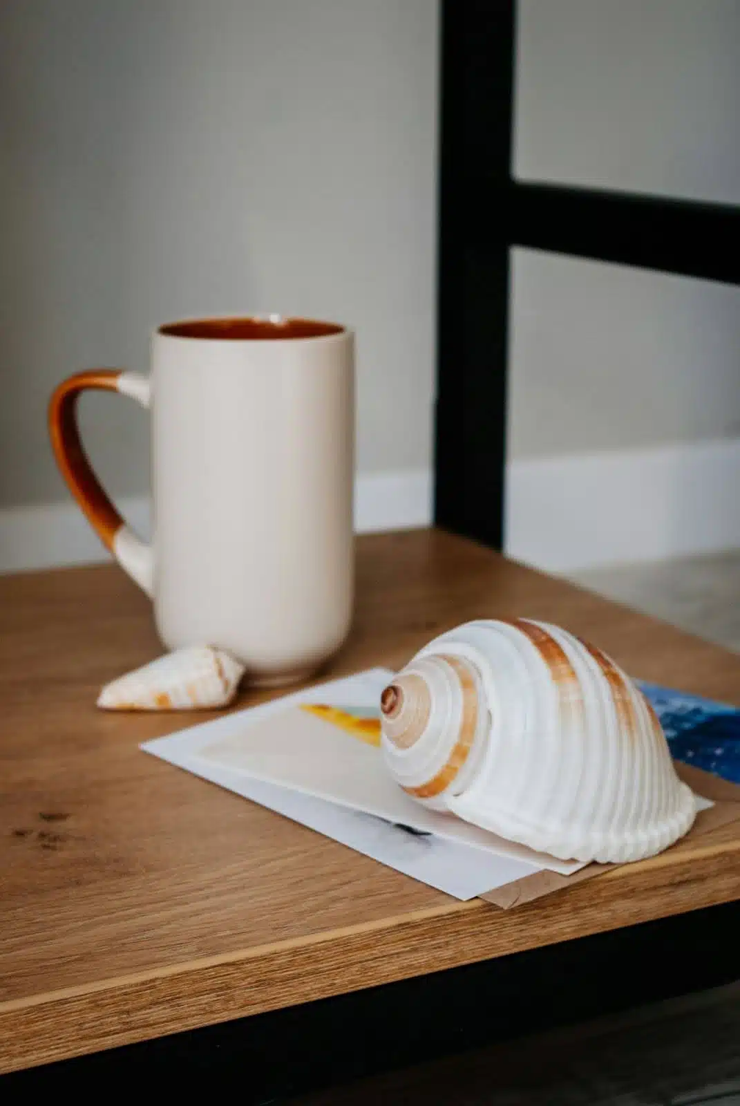 A table with seashells and a mug.